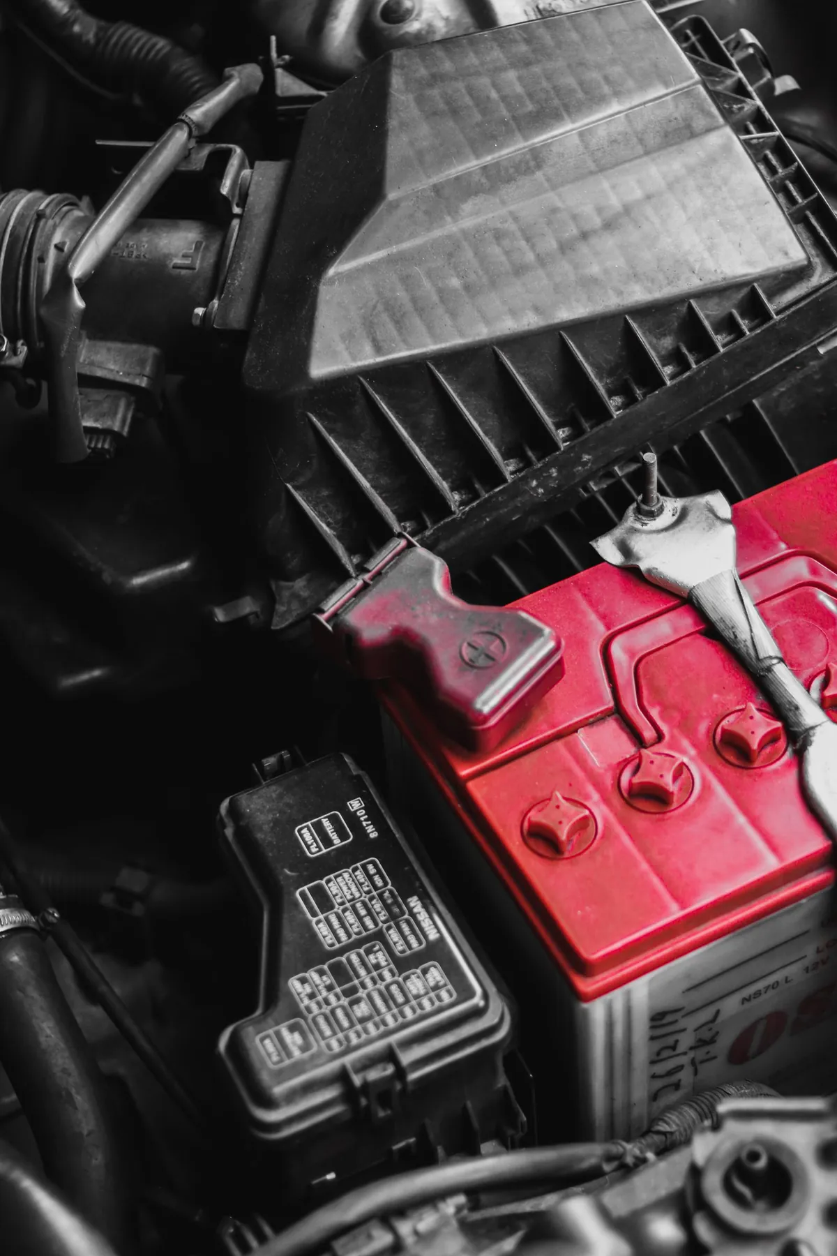 A car battery and fuse box under the hood