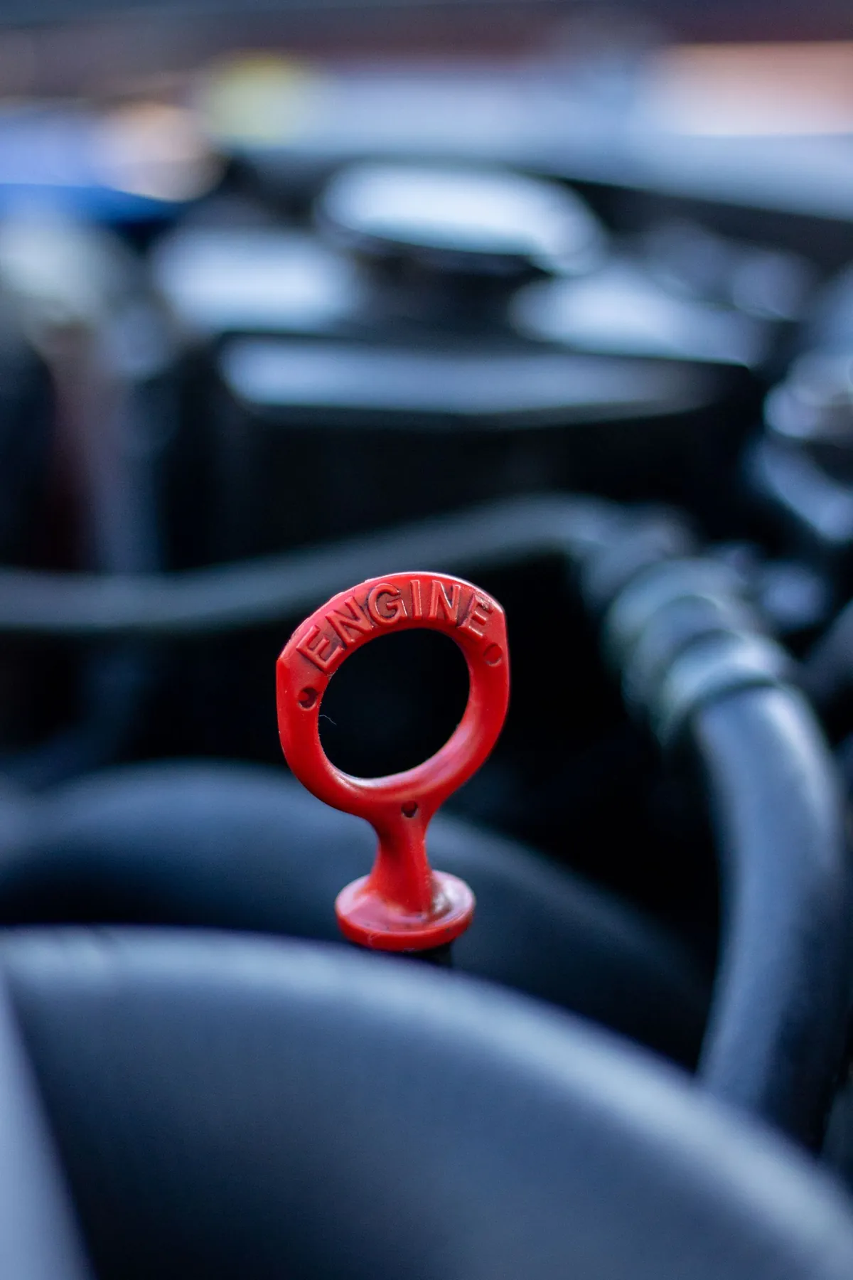 A red engine oil dipstick handle in an engine bay